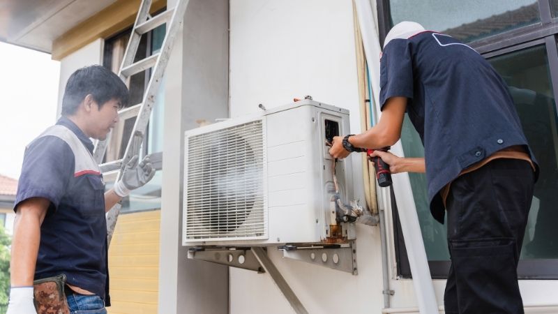 Experienced AC repair technician diagnosing a faulty air conditioning unit in Abu Dhabi